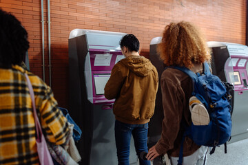 Students using self-service ticketing machine in subway station
