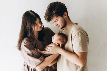 Fototapeta premium Happy mother and father hugging little baby son. Happy Mothers day and Happy Fathers day! Motherhood and parenthood. Adoption and fertility concept