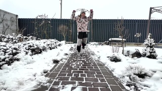 Happy girl runs along the road winter near the house