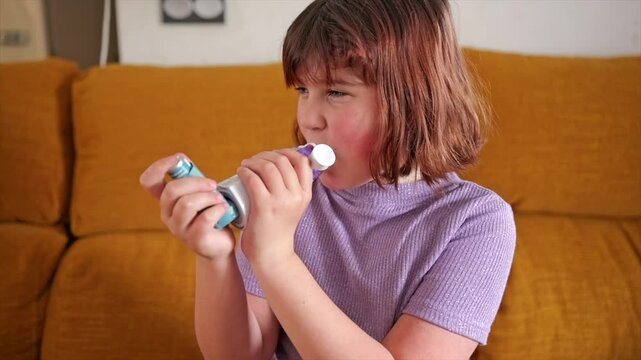 Child using asthma inhaler with determination on a cozy couch