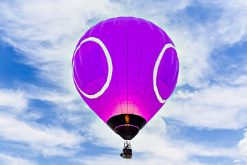Colorful hot air balloon flying over blue sky with white clouds