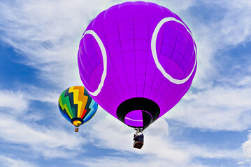 Colorful hot air balloon flying over blue sky with white clouds