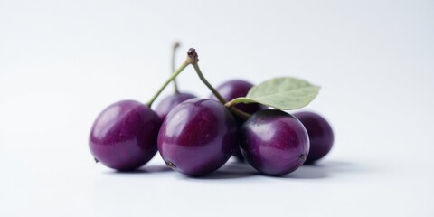 A Cluster of Deep Purple Fruits with a Single Green Leaf on a White Background