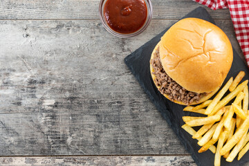Traditional sloppy joe sandwich with french fries on wooden table. Top view. Copy space