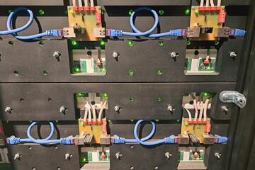 Electronic circuit board connections with blue Ethernet cables, green LED indicators