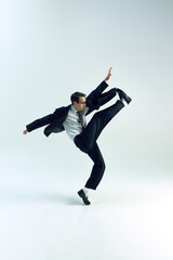 Businessman kicking high with intense focus, body stretched, jacket in motion against white studio background. Concept of business, psychology, overworked, work-life balance, success.