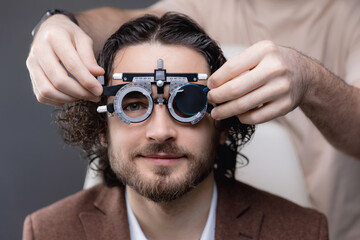 Young caucasian male getting eye exam with phoropter at optometrist office © Parilov