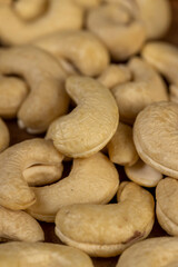large cashew nuts are scattered on a larch board