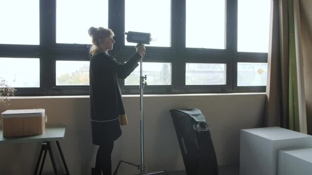 Photographer preparing flashlight and softbox grid in studio for professional lighting setup