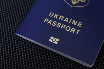 close up Ukrainian biometric passport on a dark textured background. Blue cover. Photo symbolizes travel, mobility, international travel, citizenship and freedom of movement. High quality photo