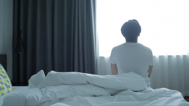 이른 아침 방의 커튼을 제치고 햇볕을 즐기는 남자