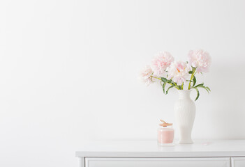 pink peonies in ceramic white vase in white interior
