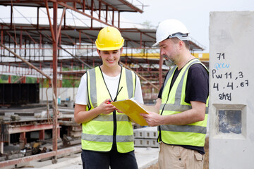 Male and female engineers working at construction site.