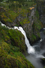 Obraz premium Majestic Waterfall Cascading Gracefully into a Lush Green Valley Surrounded by Natures Beauty