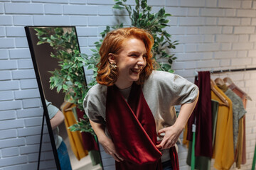 Fashion designer laughing while trying new clothes in front of mirror