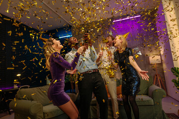 Friends celebrating birthday party with golden confetti and sparkling wine