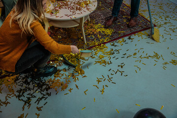 People cleaning golden confetti after party celebration