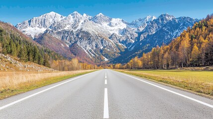 Naklejka premium Scenic Autumn Road Leading to Snow Capped Mountains