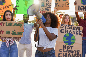 Group of young multiracial people demonstrate on the city street with climate change banner -...