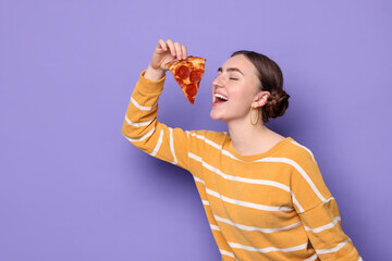 Beautiful woman with piece of delicious pizza on violet background, space for text