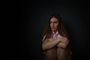Fear of darkness. Scared young woman on black background, space for text