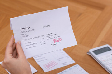 Obraz premium Paying bills. Woman with different invoices and calculator at wooden table indoors, closeup