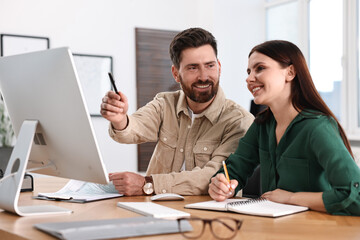 Colleagues working with computer at desk in office