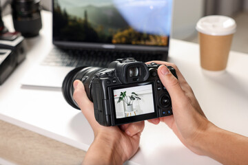 Photographer with professional camera at white desk indoors, closeup