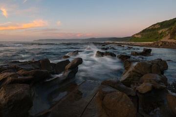 Wave flowing into rocky coastline in the morning.