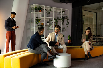 Group of coworkers chatting and collaborating in a modern coworking environment. Businesspeople...
