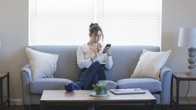 Relaxing at home while checking messages on a smartphone.