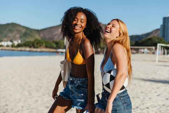 Two joyful friends laughing together on a sunny beach day - Powered by Adobe