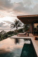 Fototapeta premium Luxurious infinity pool overlooking the ocean, modern boho patio with minimalist furniture, serene atmosphere, golden hour lighting, tropical vibes