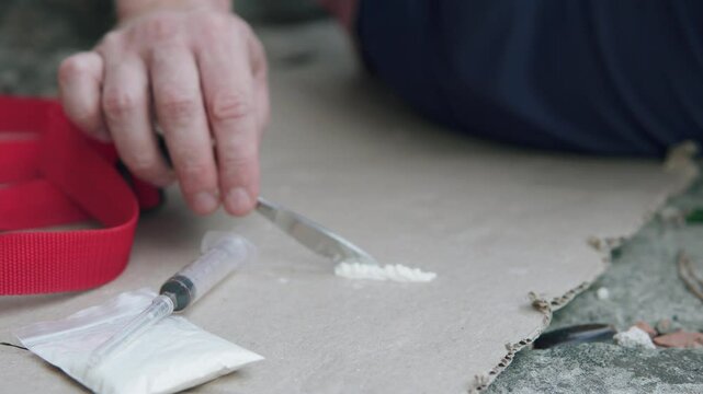 A drug addict prepares lines of heroin and fentanyl. The concept of alcohol and drug addiction.
