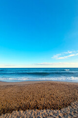 Tranquil Beach Scene with Clear Blue Sky and Gentle Waves for Summer Relaxation