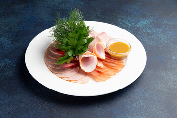 Assortment of meat delicacies in a plate on a dark background.
