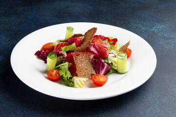 Salad with salmon in a plate on a dark background.