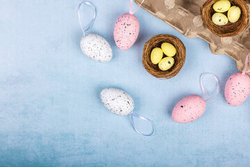 Easter pink and white eggs in an egg stand on a blue background, painted quail and chicken eggs for Easter, real farm eggs just from the hen, copyspace, Easter and spring concept