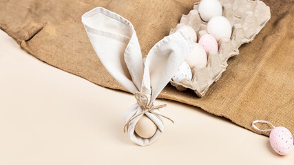 Napkin folded in the shape of rabbit ears with an egg inside, Farm natural eggs in an egg holder on...
