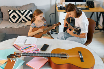 Fototapeta premium Mother and daughter play musical instruments together in living room setting during afternoon
