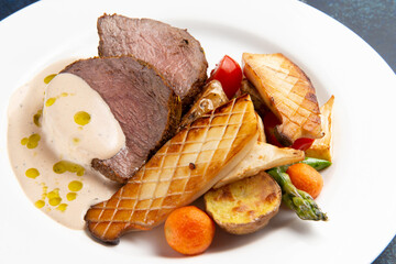 Steak, fried vegetables and mushrooms in a plate on a dark background.