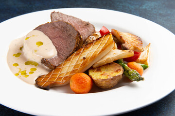 Steak, fried vegetables and mushrooms in a plate on a dark background.