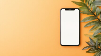 Blank smartphone placed on an orange background with green leaves beside it creating a vibrant and modern contrast