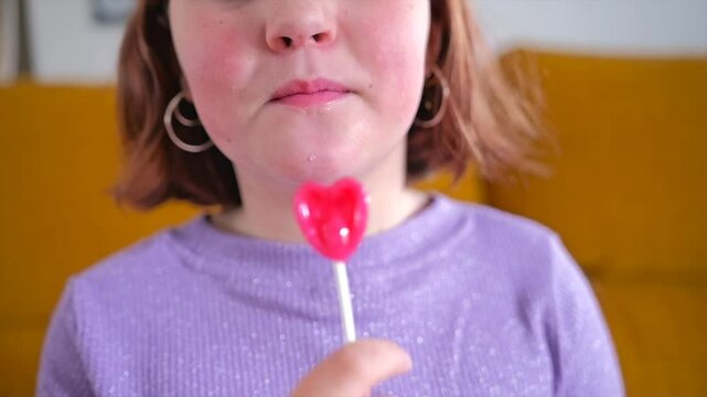 Child enjoying a heart-shaped lollipop while smiling with delight