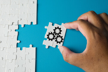 Hand holding puzzle piece with gears icon concept for teamwork and business strategy, process optimization, innovative solutions, efficiency, workflow improvement,problem-solvingand corporate growth.