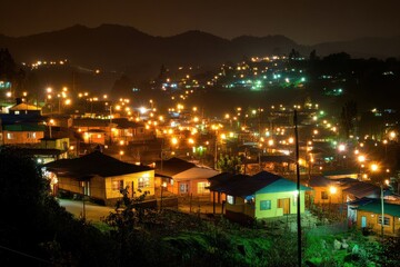 Obraz premium Nighttime Glow of a Serene Village with Twinkling Lights and Hills