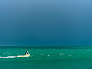 A long shrimp boat heads towards the harbor in the gulf ahead of the storm remnants of Hurricane Milton fighting through the white caps on the turquoise waters