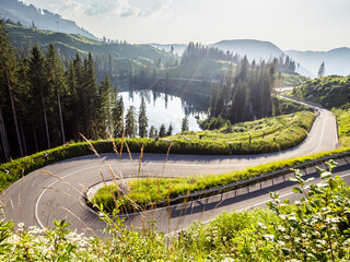 Carretera serpenteante en paisaje montañoso con lago y bosque