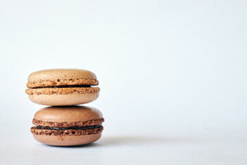 Stack of two brown French Macarons, cakes with different flavors, coffee and creme brulee flavor. pyramid of homemade dessert, macaroons side view, Copy space for text