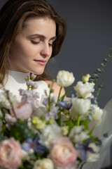 Caucasian young female with bouquet of spring flowers in soft light
